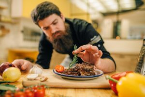 Chef decorates herbs roasted meat slices in plate