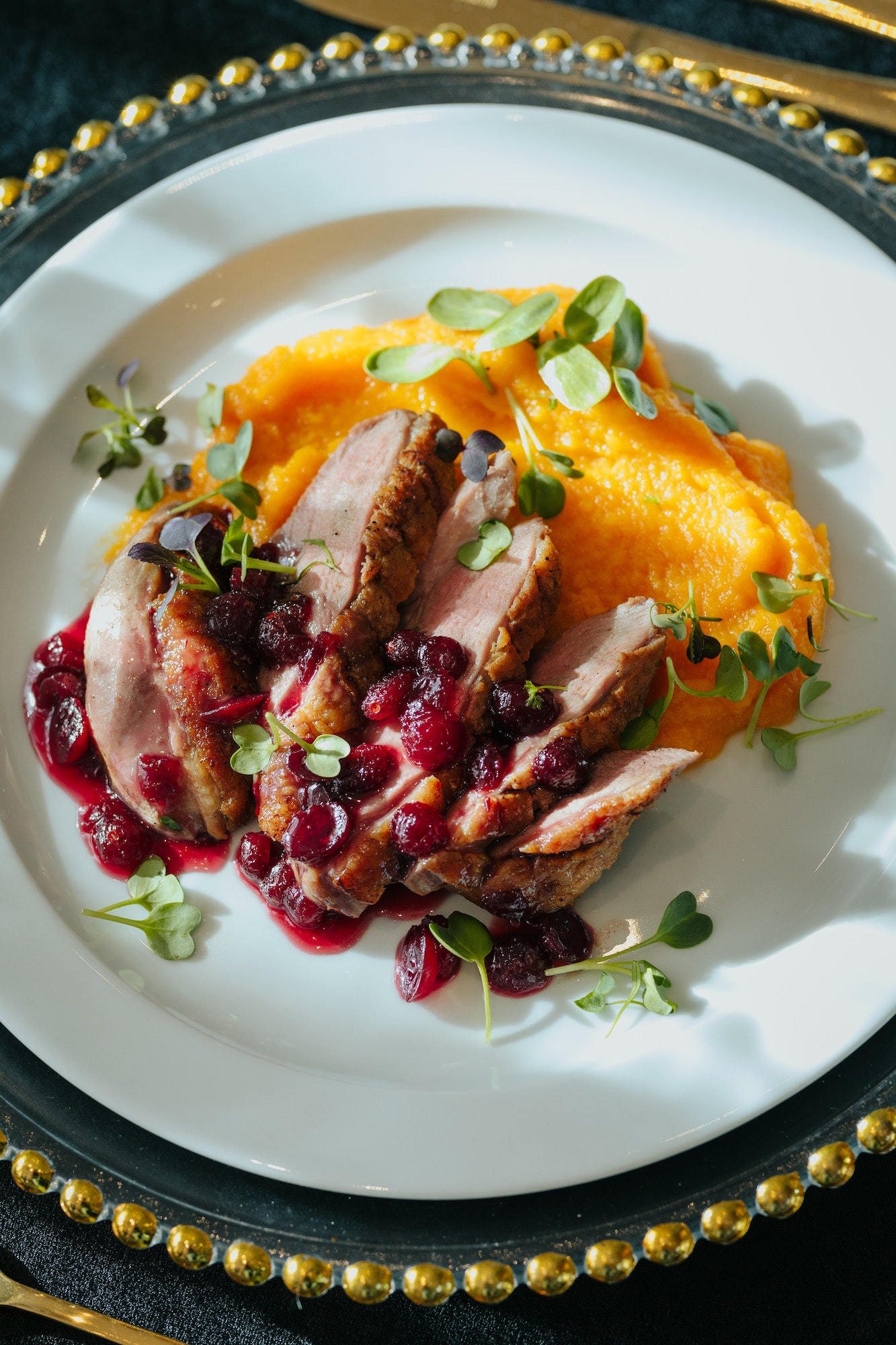 Colorful plate with meat, cheese and mashed vegetables surrounded by golden cutlery