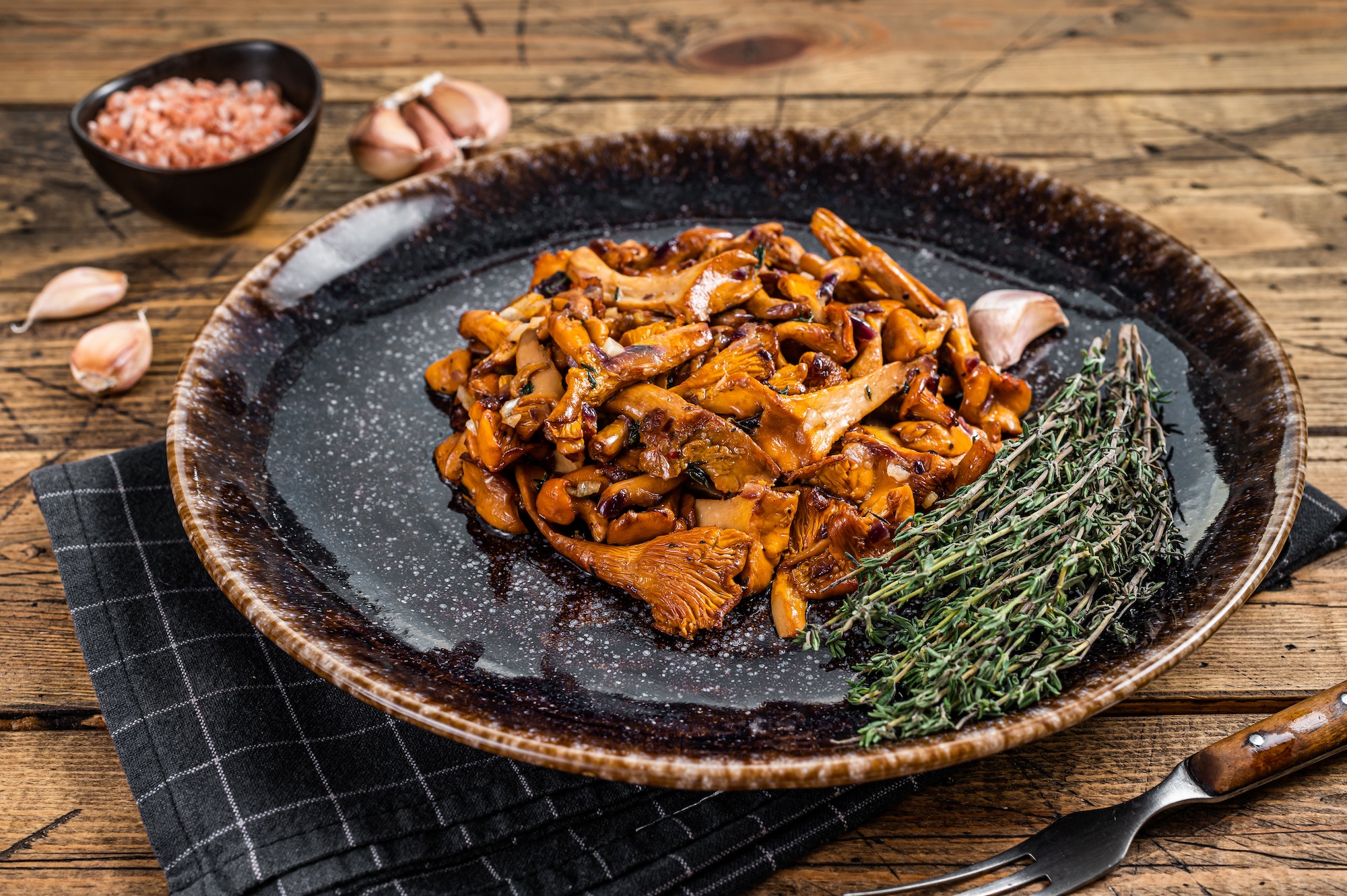 Cooked wild fried chanterelle mushrooms with onions and herbs. Wooden background. Top view