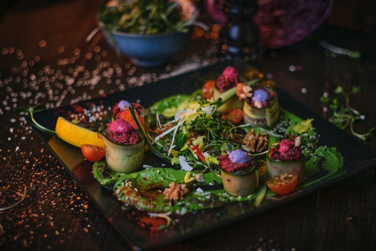 Haute cuisine vegetarian plate of appetizer rolls and a bowl of herbs served on a wooden table