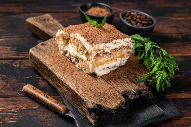 Italian dessert Tiramisu cake with cocoa and mint on a wooden board. Dark