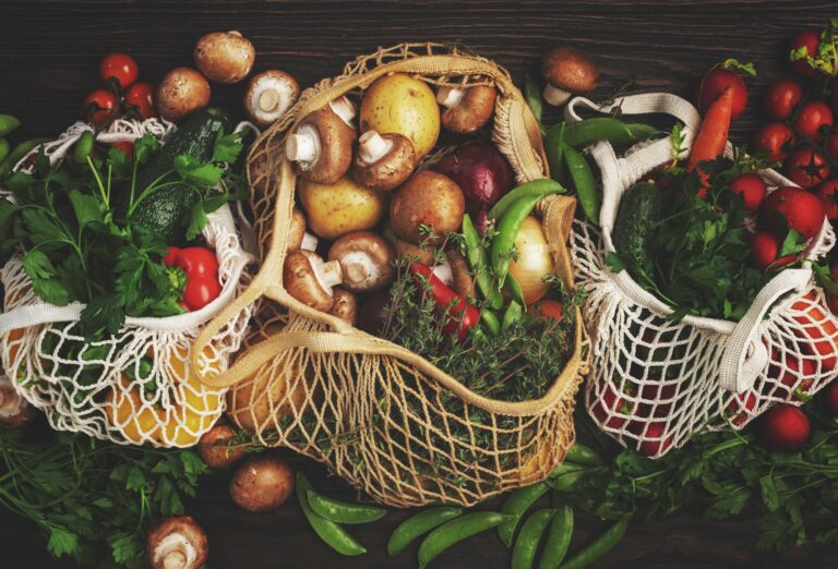 Reusable shopping textile bags full of organic spring vegetables from local farmers market