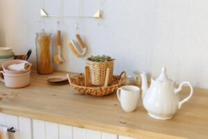 White cup of tea with a teapot on the background of the kitchen interior.